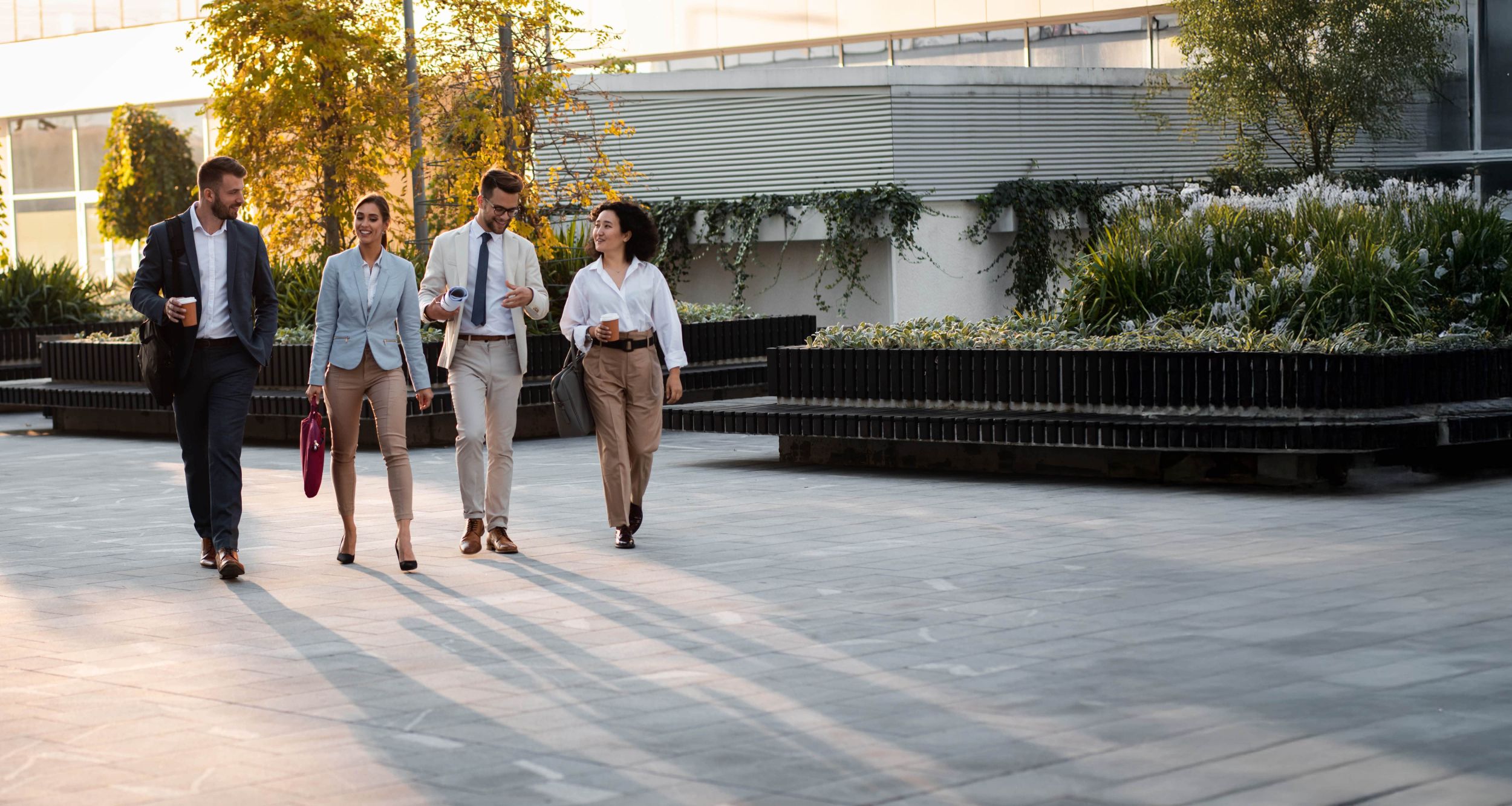 Vier Mitarbeiter gehen durch das Eingangsgelände der Firma.
